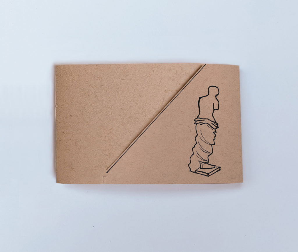 Closed book, a small horizonal rectangle shape: the cover is a pale pink-brown cardstock, toward the right edge is a black ink outline drawing of the Venus de Milo sculpture. A black diagonal line cuts across the cover from upper right to lower left - this is the edge of the overlapping flap that keeps the book closed.